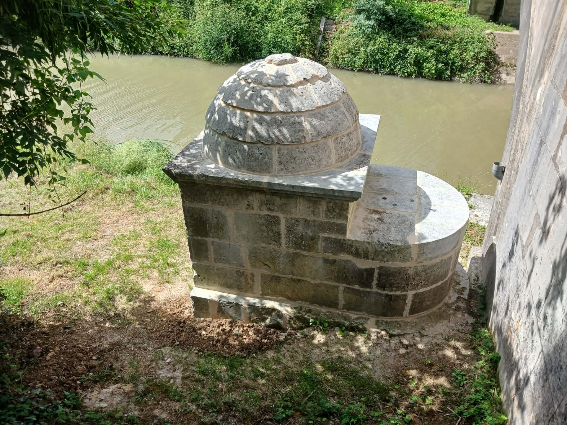 Le dôme de pierre et la margelle circulaire de la fontaine restaurée