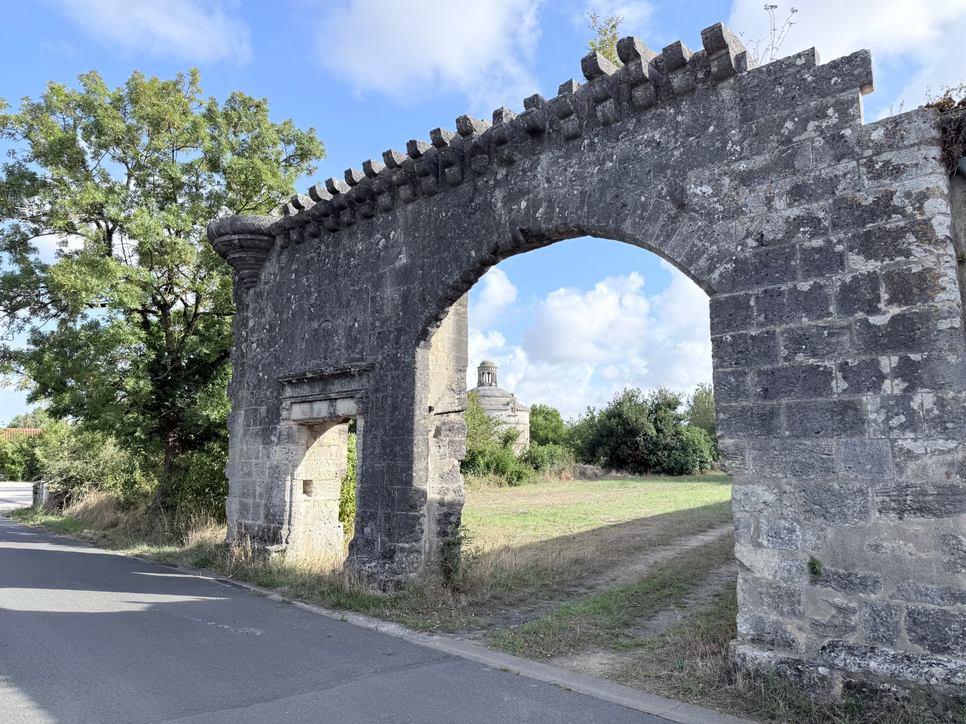 La grande arche de la porterie du prieuré Saint-Sauveur, avec le dôme du pigeonnier visible au loin