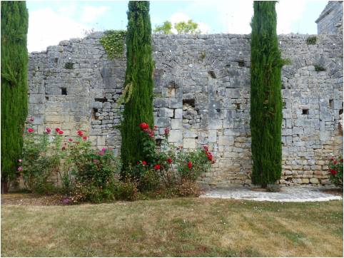 Mur d'enceinte en pierre du prieuré de Moustierneuf, bordé de cyprès et de rosiers