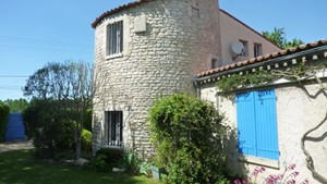 Tour de moulin intégrée à une maison aux volets bleus