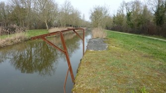 Potence métallique rouillée dressée au bord du canal de la Bridoire face au quai de pierre