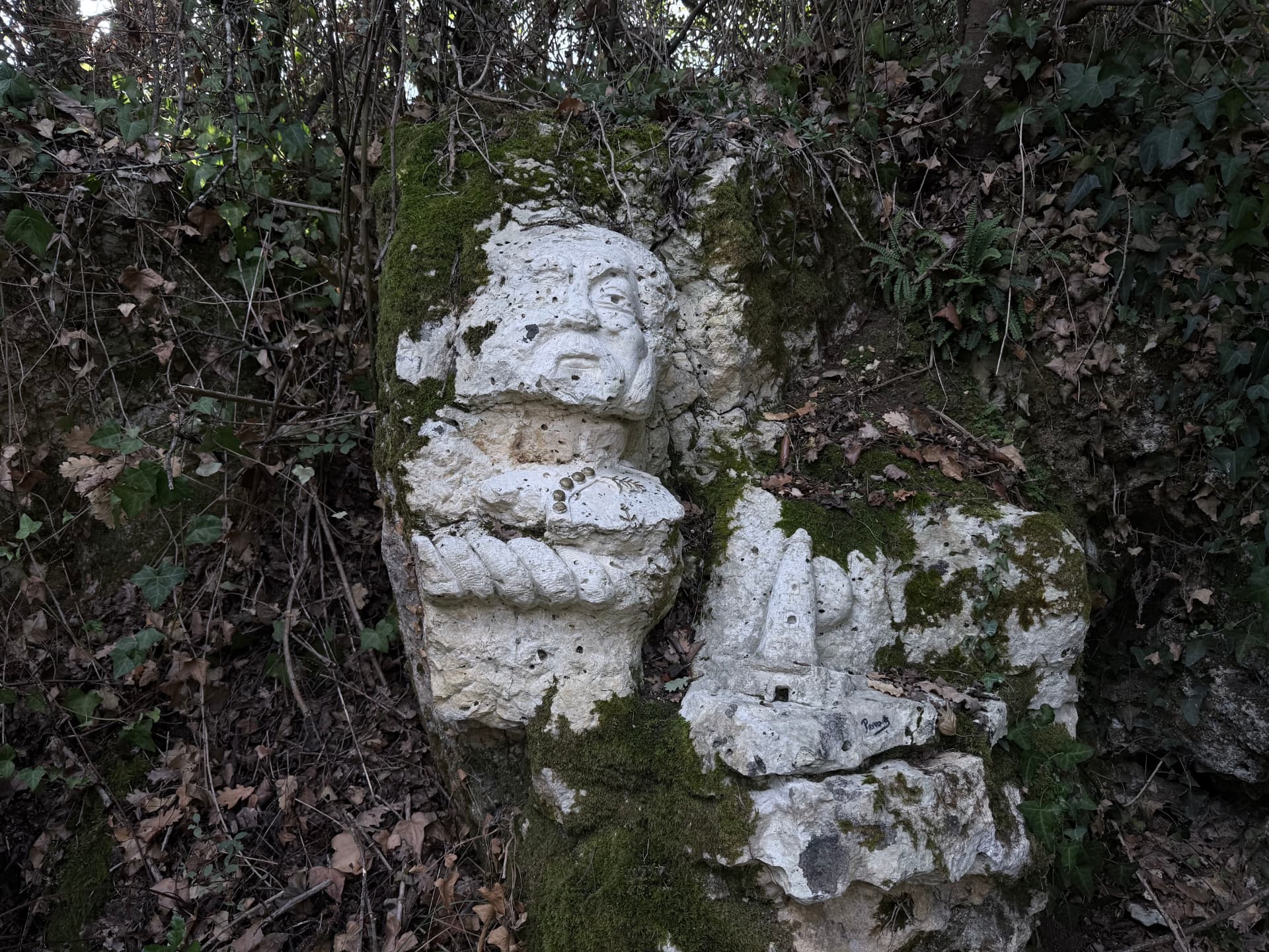 Visage barbu sculpté dans la roche, envahi de mousse et de lierre