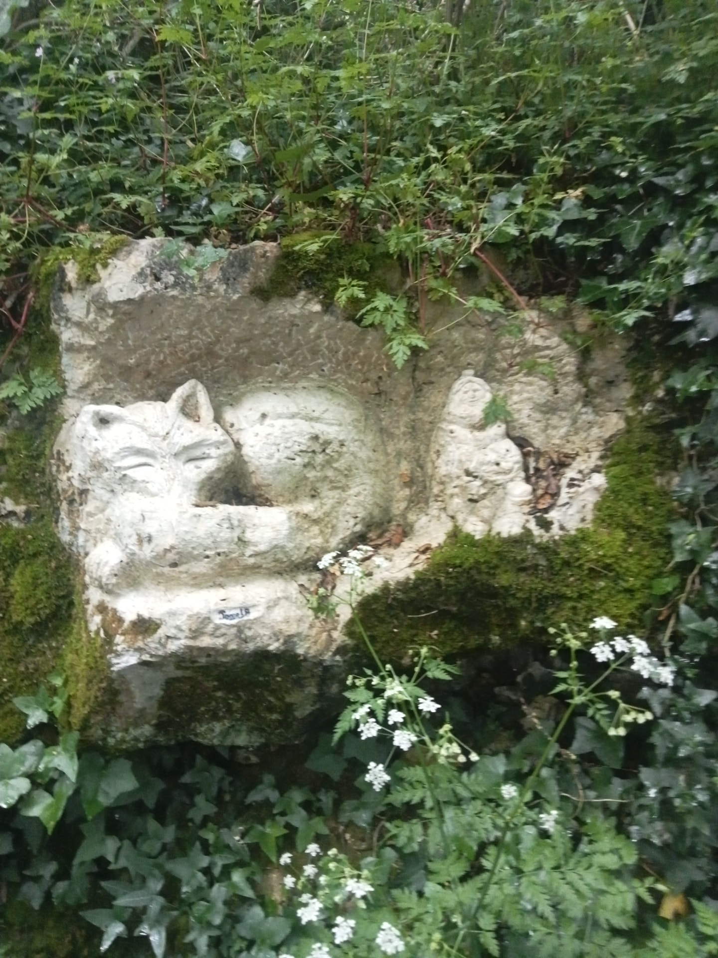 Chat endormi et petit personnage sculptés dans un bloc calcaire
