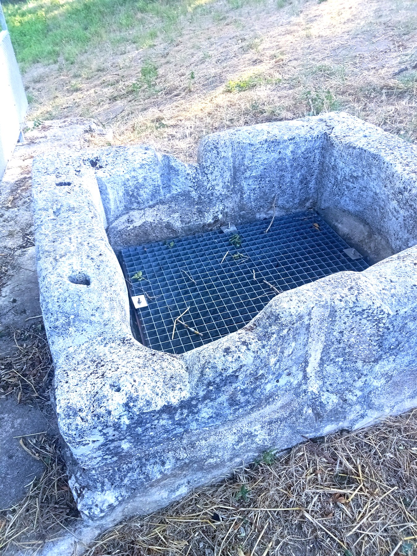 Margelle du puits en pierre marquée par les rainures de cordages