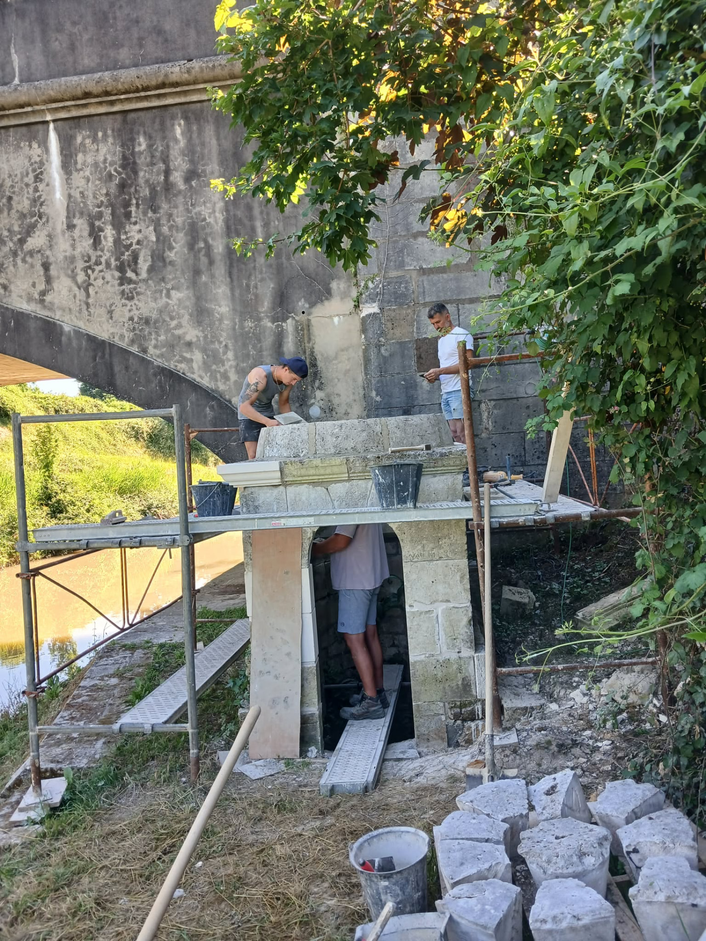 Deux artisans posent les pierres de la corniche de la fontaine