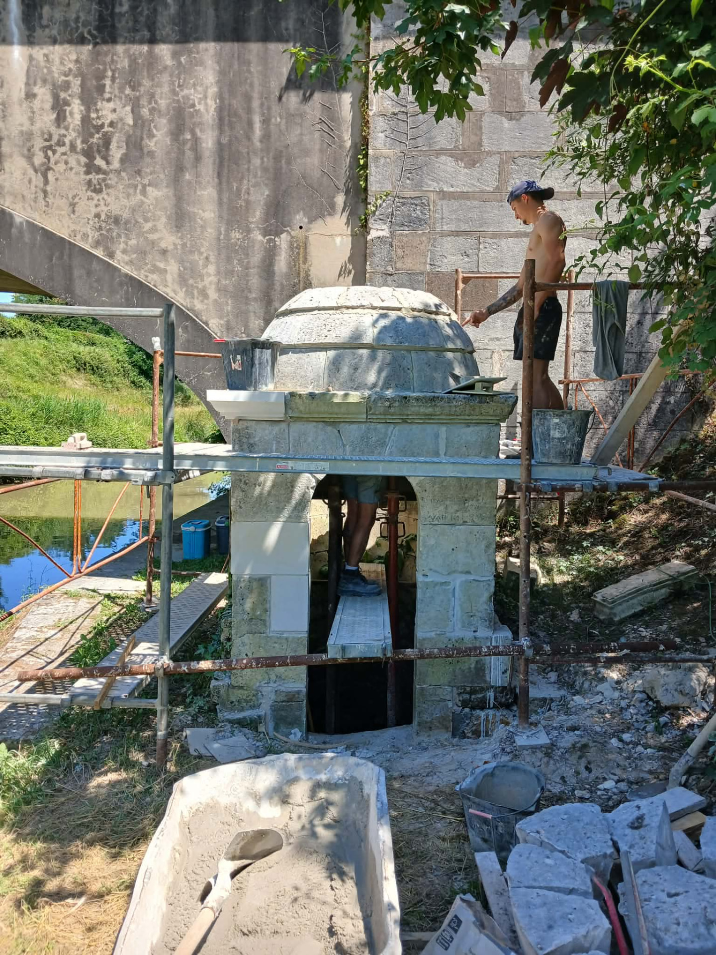 Un tailleur de pierre remonte le dôme de la fontaine sur l'échafaudage