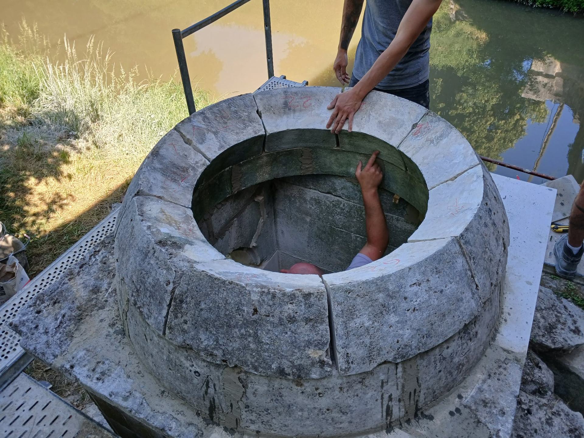 Vue plongeante sur la margelle circulaire du puits en cours de remontage